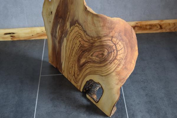Handgeschnitzter Olivenholz "Dino"  Dieses einzigartige Olivenholz-Dekoelement besticht durch seine beeindruckende Maserung und geschwungene Form. Besonders hervorzuheben ist die elegante Kante am unteren Rand, die dem Dino seinen charmanten Charakter ver